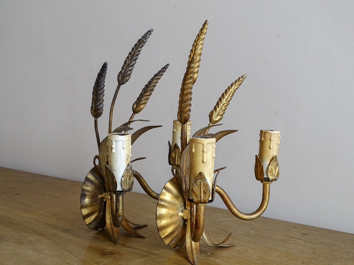 Angled side view of paired mid-century wheat sheaf wall sconces in gilt metal