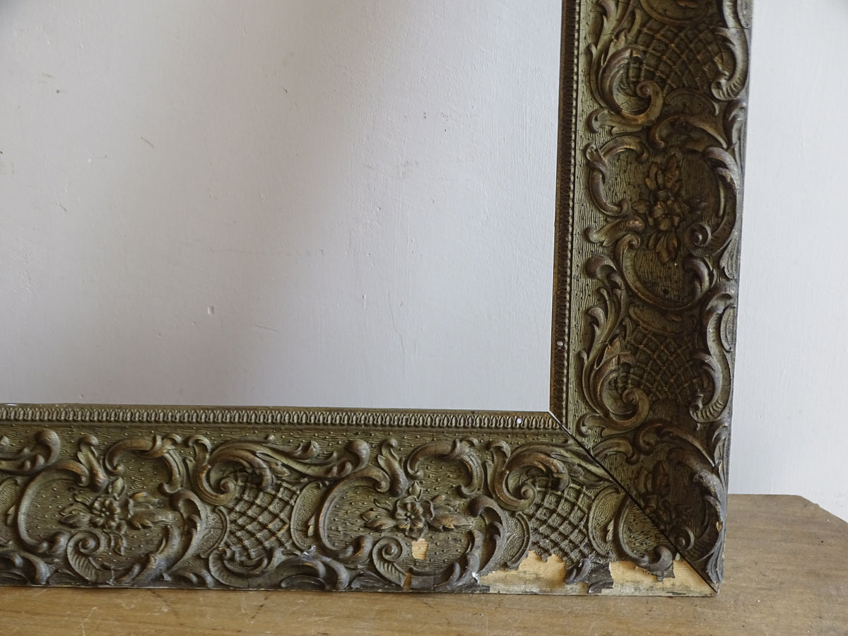 Lower right corner of French antique frame showing aged finish, floral scrollwork and areas of decorative loss