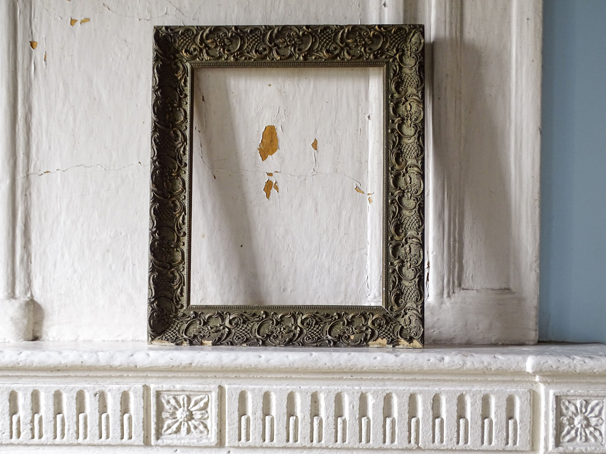 Full view of French 19th-century ornate Louis XV style frame with aged green-grey and gilt finish displayed on a country fireplace
