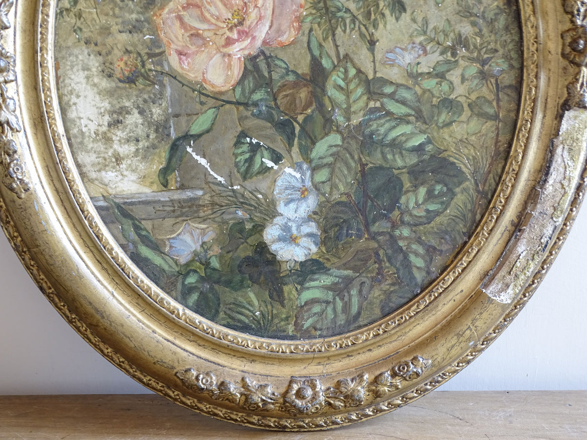 Close-up of floral ornament and aged gilding on the antique oval frame
