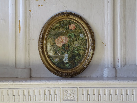 French antique floral painting on ceramic in an ornate gilt oval frame from the 19th century displayed on a French country fireplace
