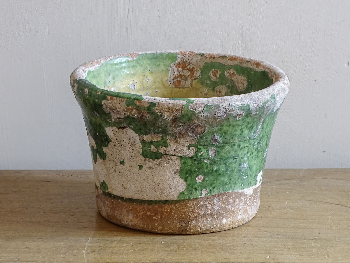 Antique French earthenware pot with worn green glaze and terracotta base
