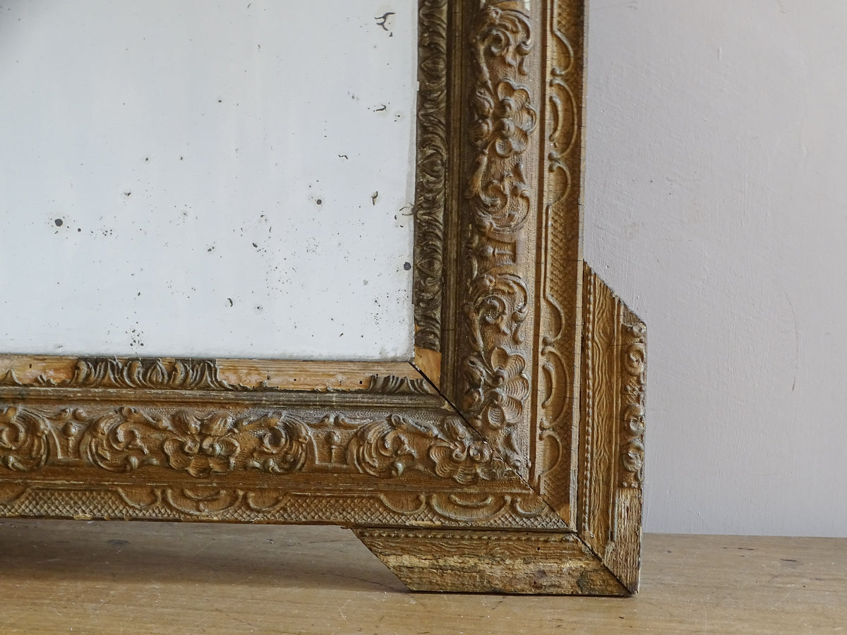 Close-up of aged gold finish and moulded stucco decoration on a French antique mirror