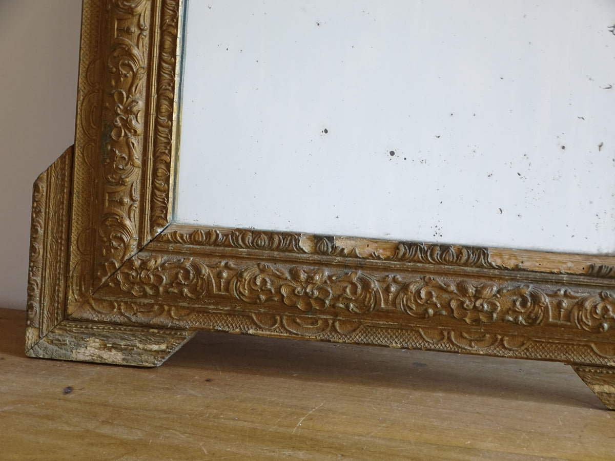 Close-up of aged gold finish and moulded stucco decoration on a French antique mirror