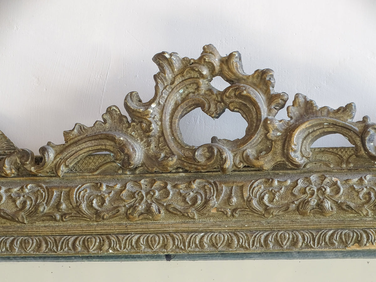 Pierced rocaille-style crest on an antique French giltwood and stucco mirror