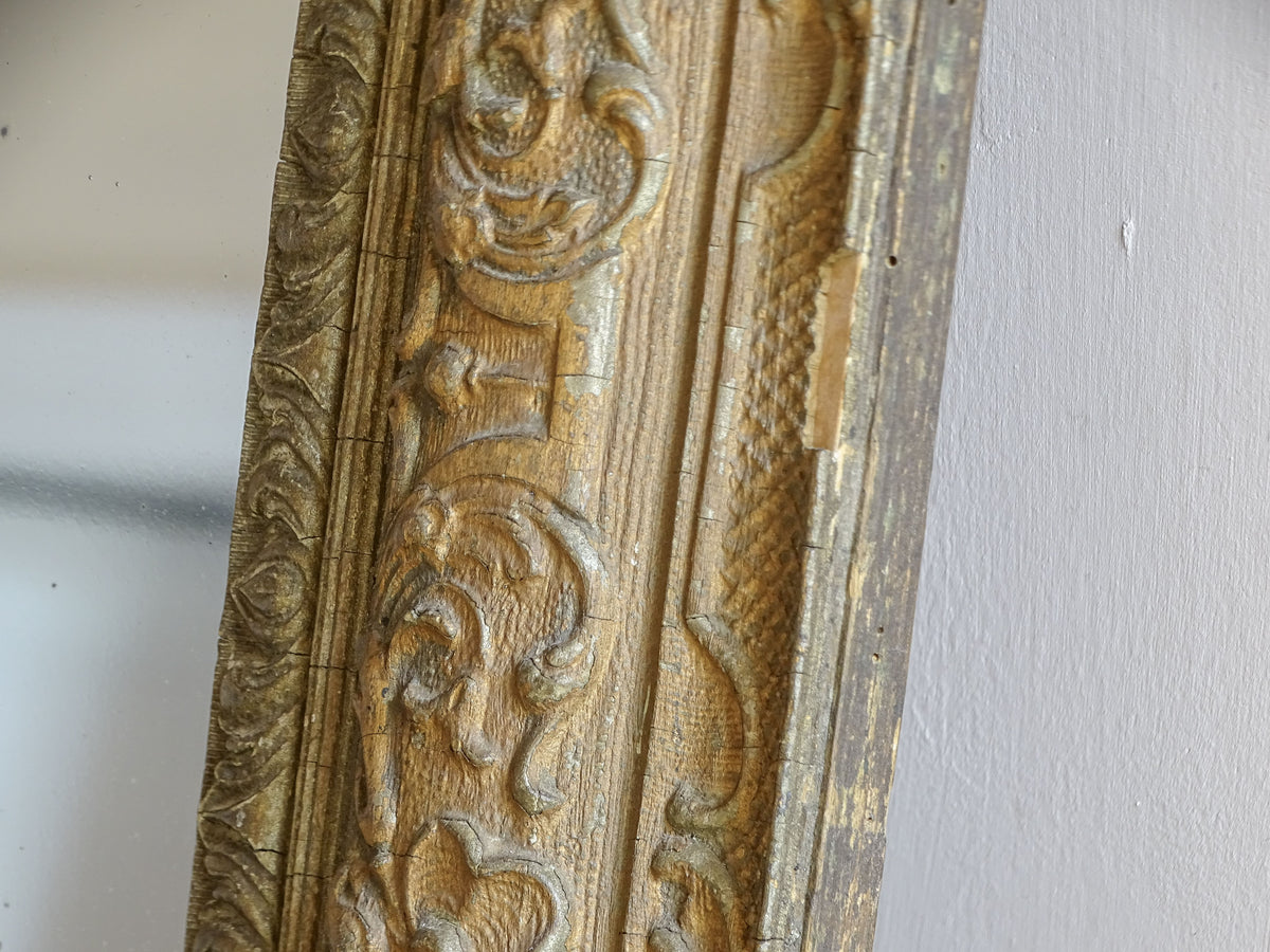 Close-up of aged gold finish and moulded stucco decoration on a French antique mirror