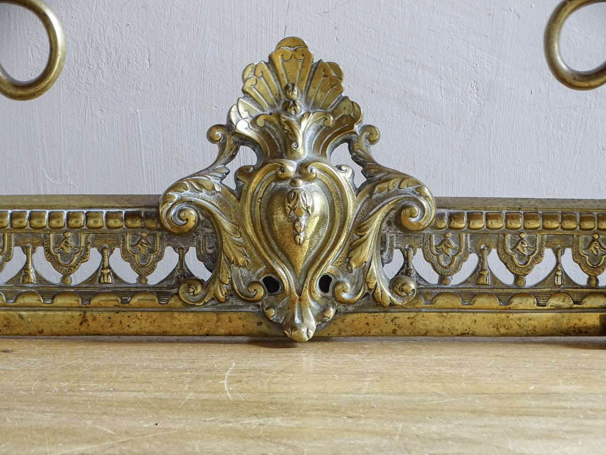 Central rocaille cartouche on an antique French Napoleon III brass fireplace fender