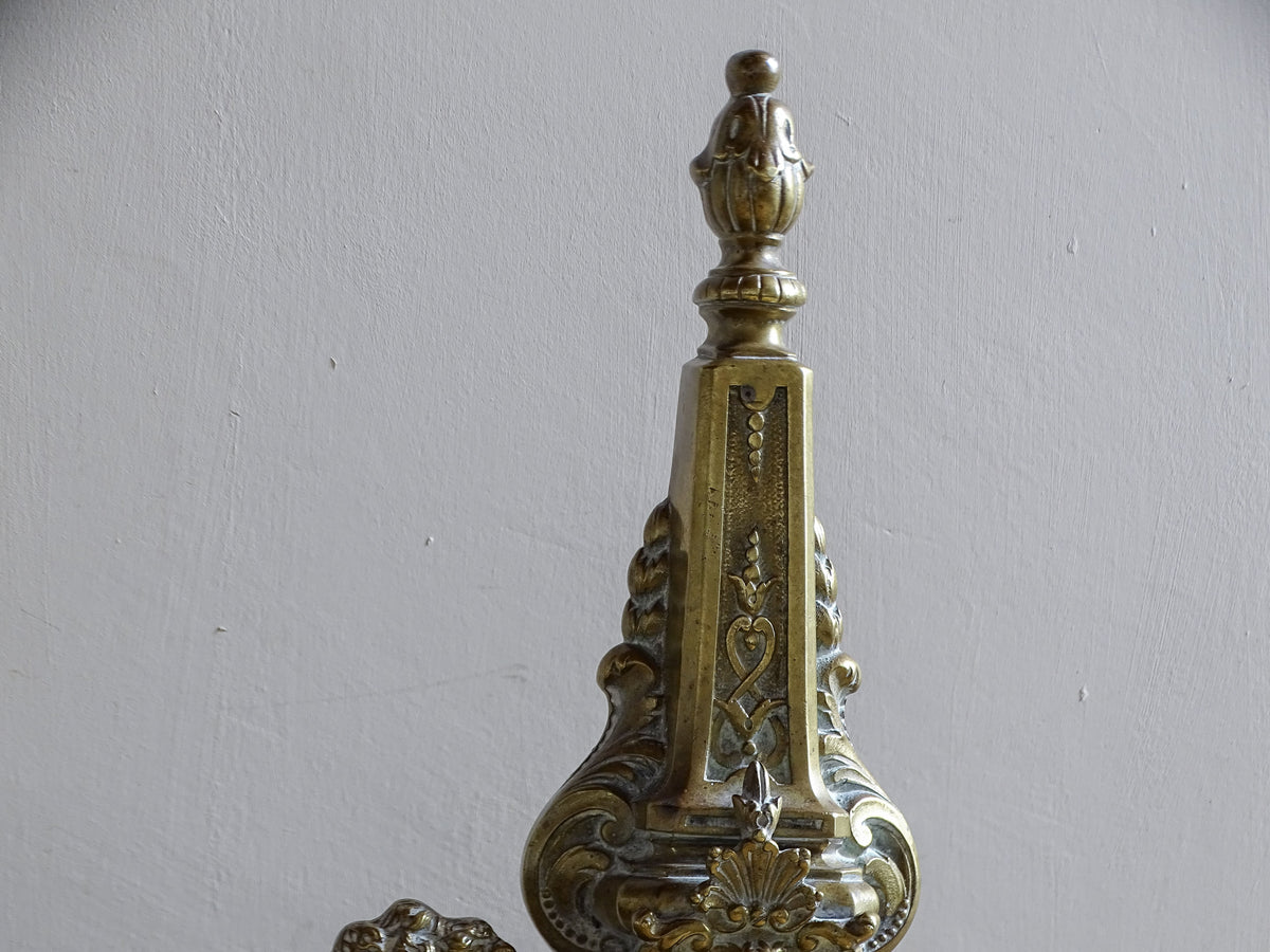 Ornate upright with scrolling decoration on a Napoleon III brass fireplace fender