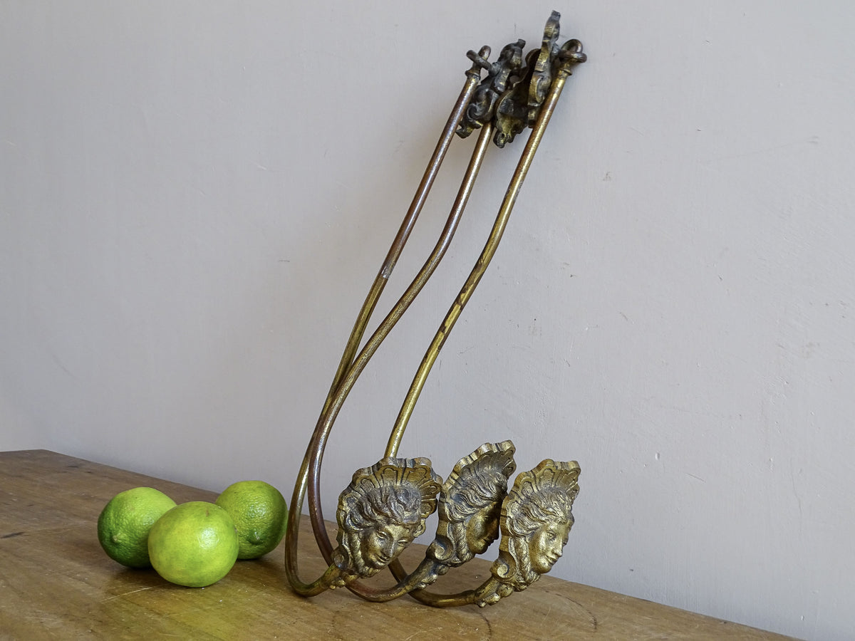 Detail of classical female faces on French antique gilt metal curtain holdbacks