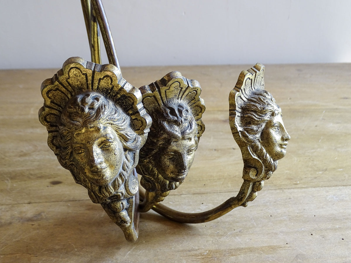 Detail of classical female faces on French antique gilt metal curtain holdbacks