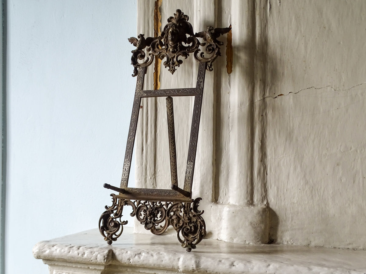 Side view of an ornate 19th-century German cast iron display easel with decorative scrollwork and folding support