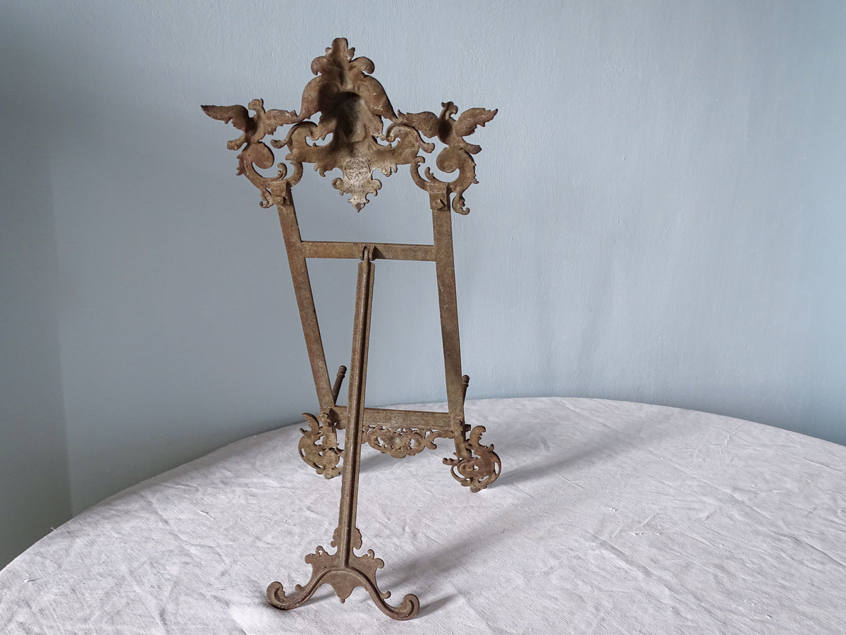 Reverse of the ornate cast iron crest of an antique E.G. Zimmermann easel, showing the two birds and foundry stamp