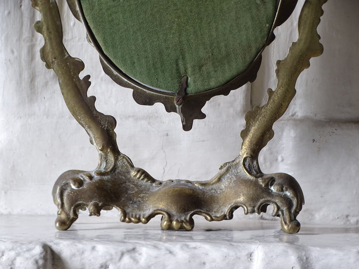 Detailed rear view of the decorative cast brass base and scrolling supports of a French Rococo-style dressing table mirror