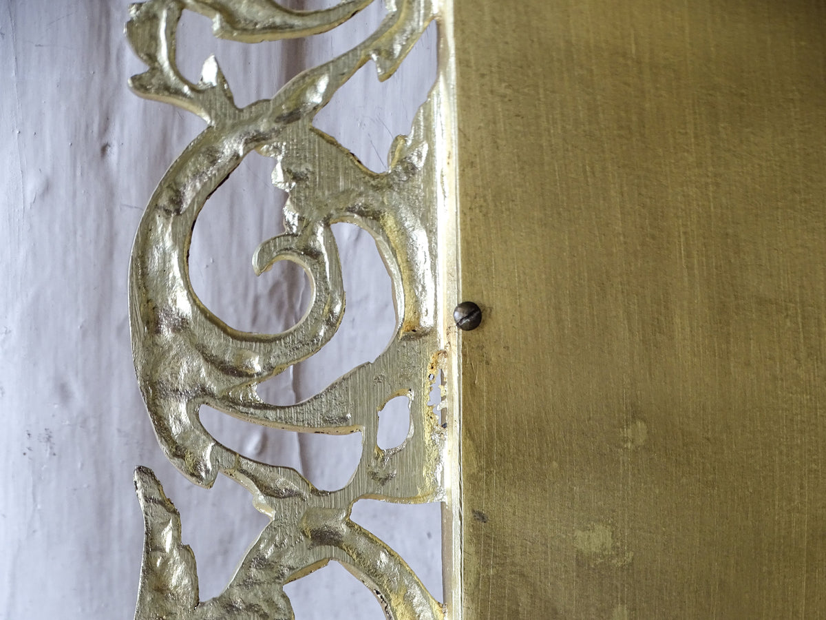 Detail of the antique mirror's metal backing plate, slotted screws and ornate gilt metal frame