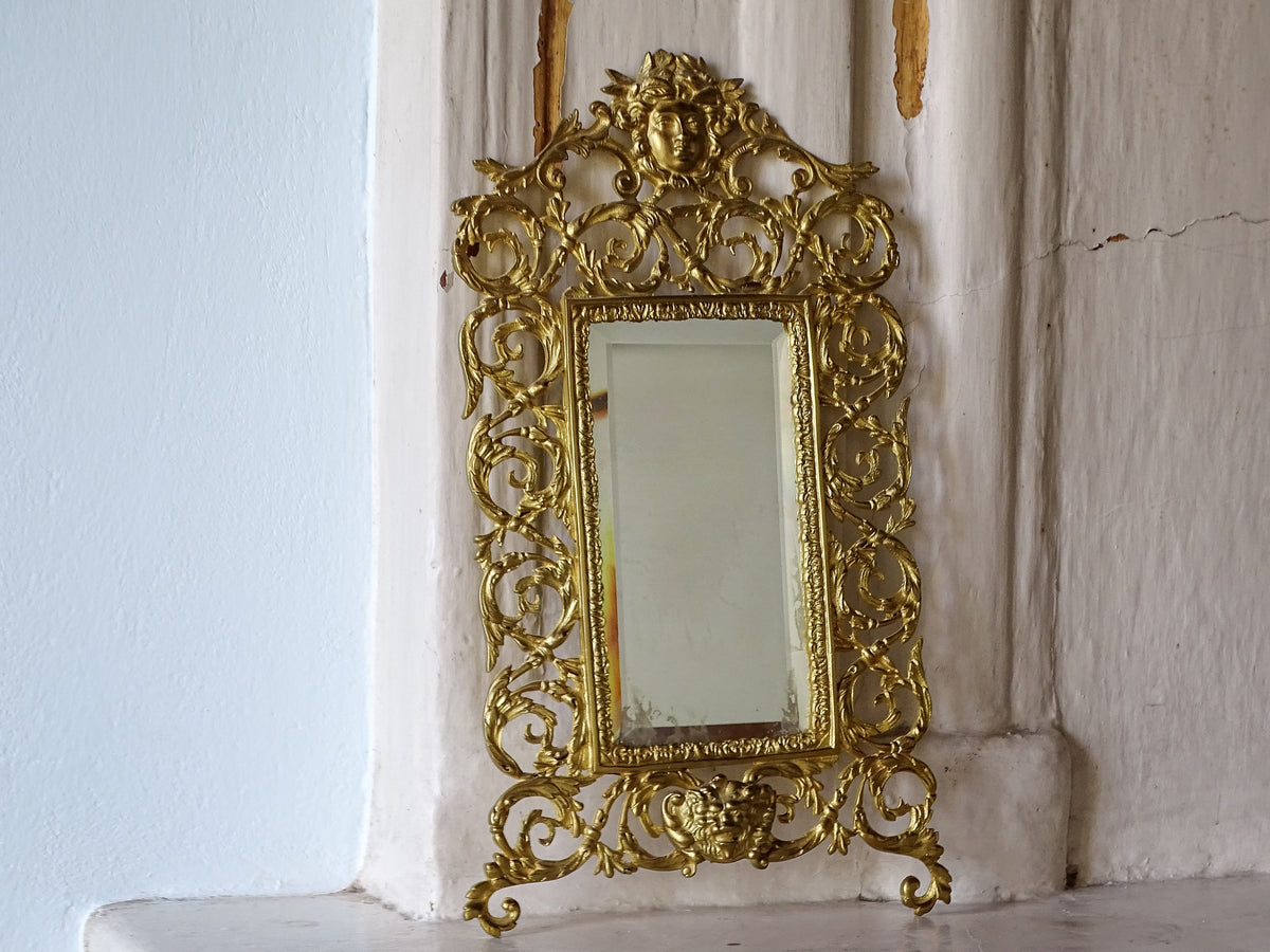 Full view of a 19th-century French gilt metal mirror featuring sculptural foliage and aged bevelled mirror glass