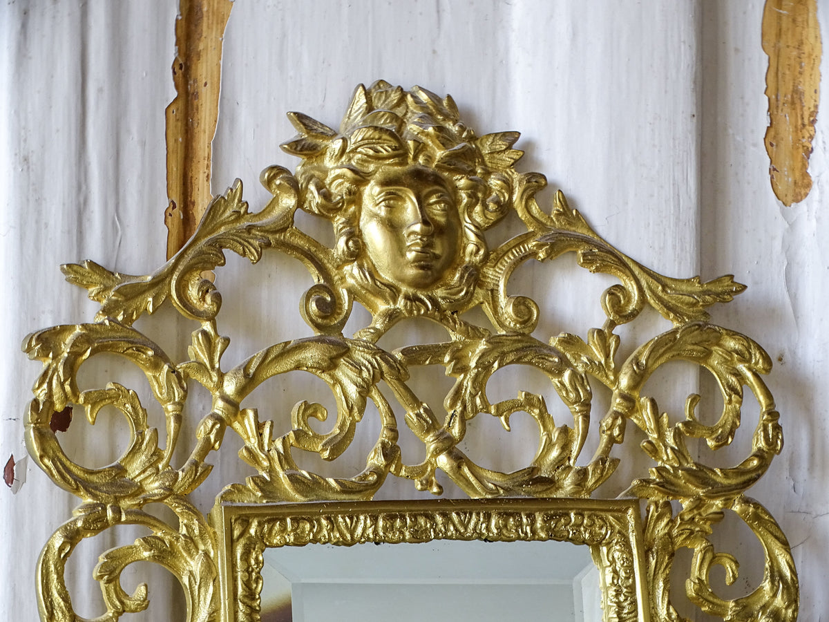 Upper section of an antique French gilt metal mirror with elaborate openwork foliage and a classical female mask