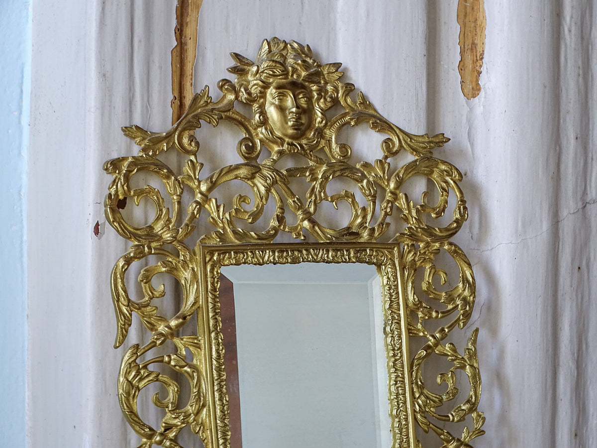 Upper section of an antique French gilt metal mirror with elaborate openwork foliage and a classical female mask
