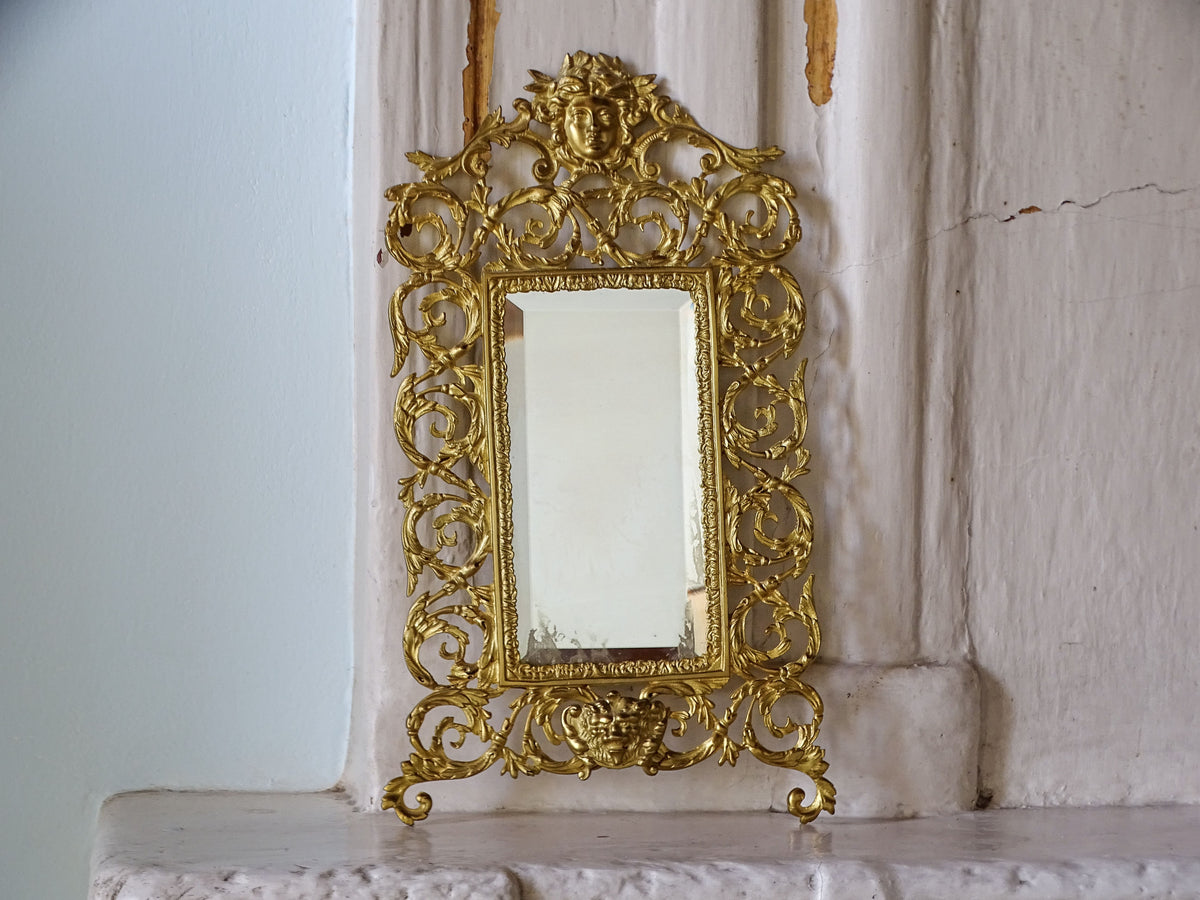 Antique Napoleon III wall mirror with an elaborate gilt metal frame and visible age-related wear to the bevelled glass