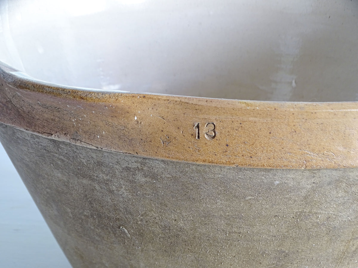 Close-up of the number 13 impressed into the caramel glazed rim of a French vintage stoneware mixing bowl.