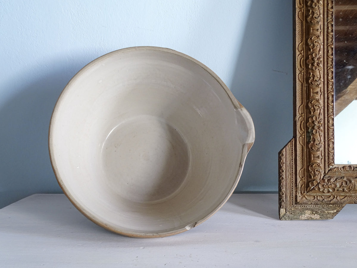 Overhead view of a French vintage mixing bowl with a smooth cream-glazed interior and pouring spout.