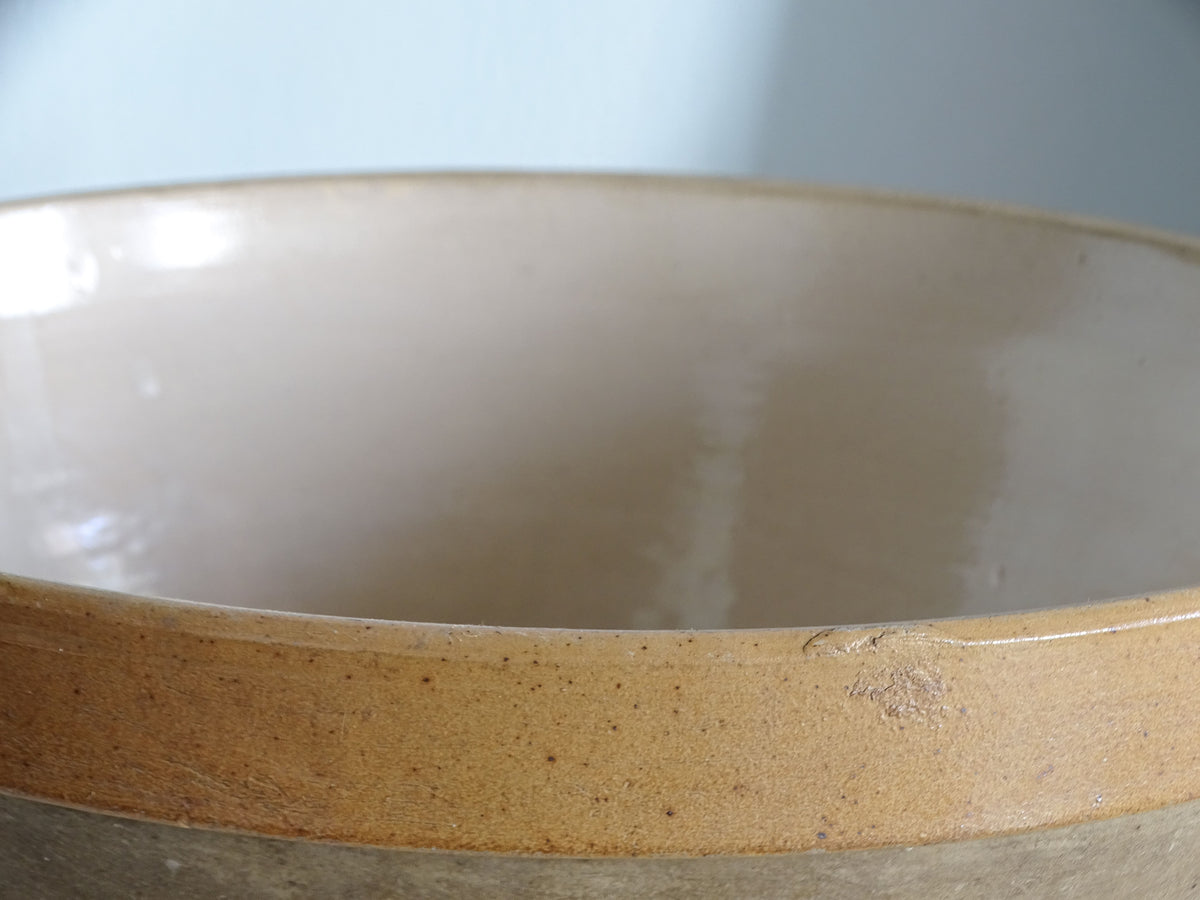 Detail of the honey-coloured glazed band and surface wear on a traditional French stoneware bowl.