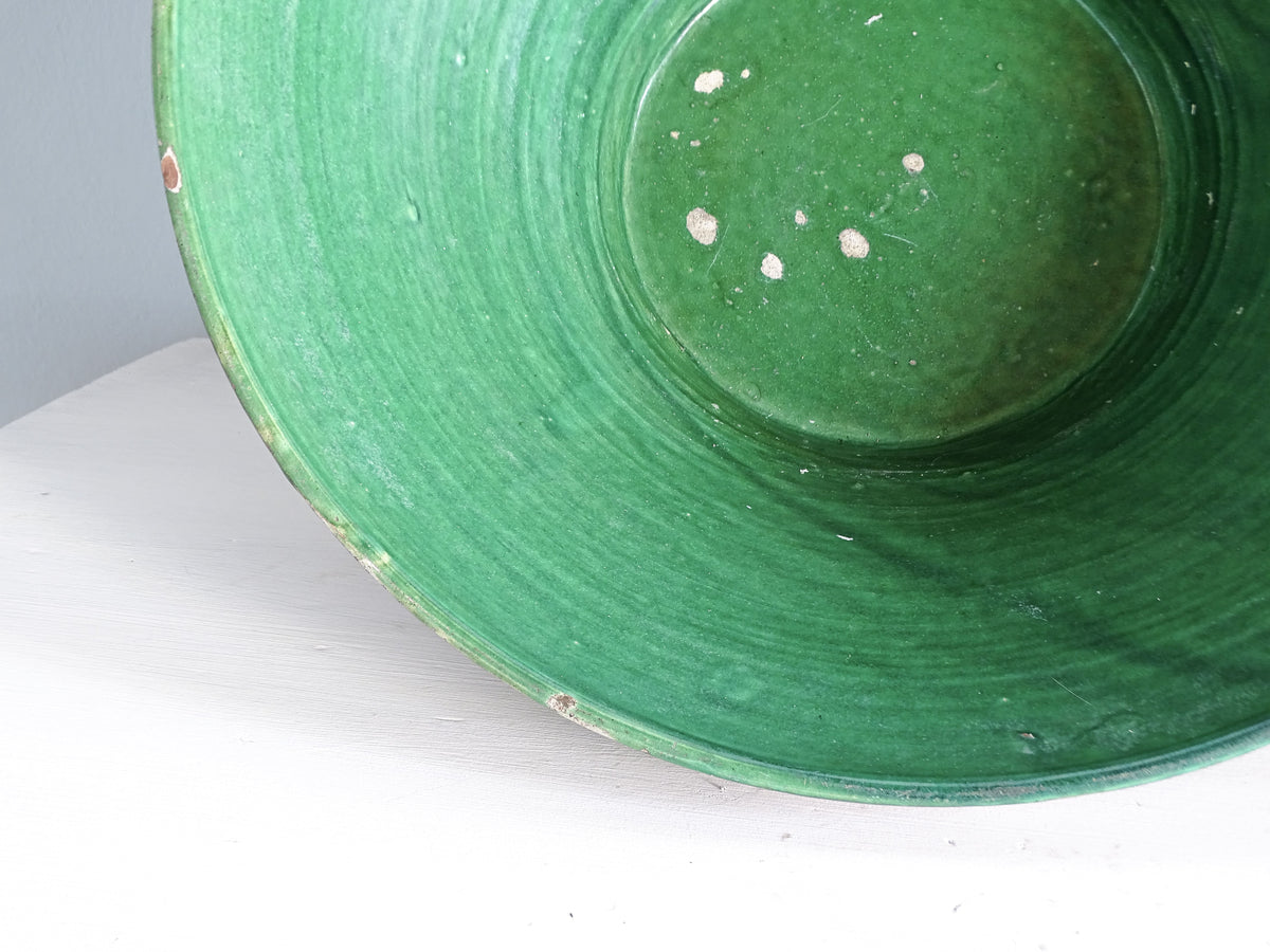 Interior of a 19th-century French green glazed tian bowl showing its wide, gently sloping sides and aged glaze.