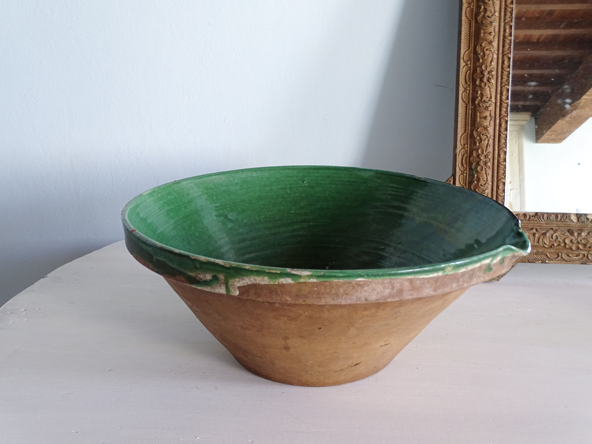 Side view of a large 47 cm antique French tian bowl with deep green glazed interior, terracotta exterior and pouring lip.