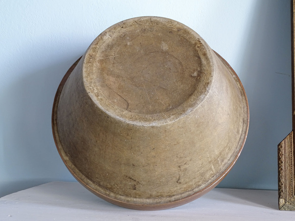 Base and unglazed exterior of an early 20th-century French pottery mixing bowl with signs of age and use.