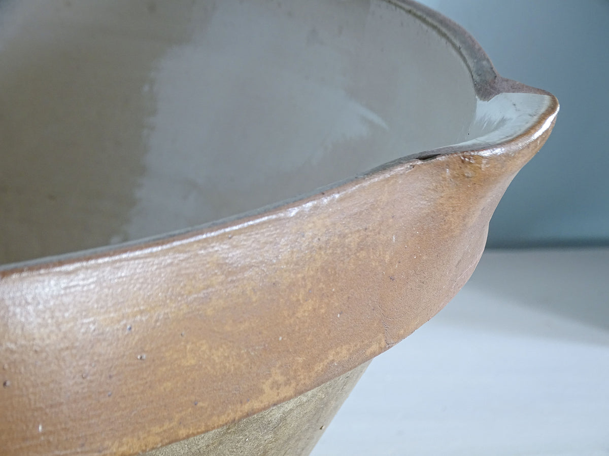 Detail of the pouring spout and small rim chips on an early 20th-century French antique mixing bowl.