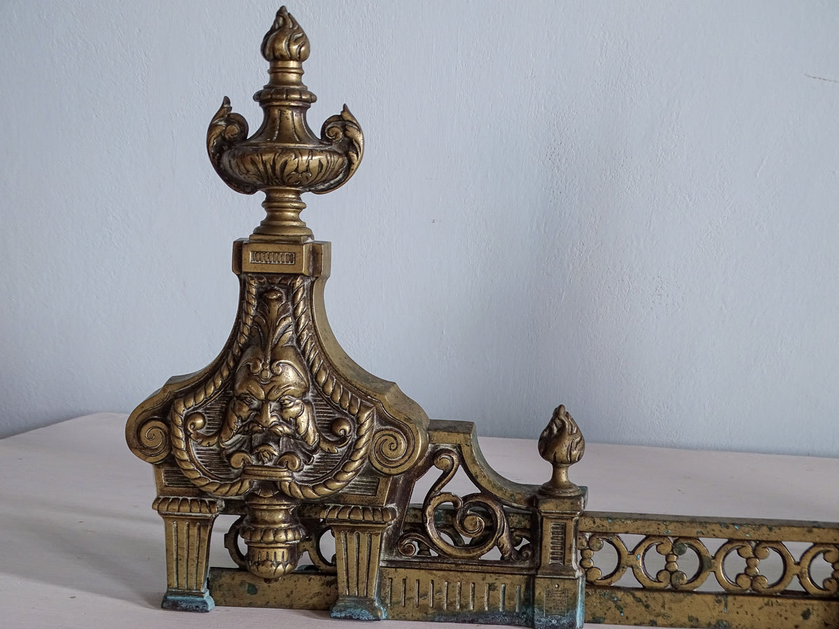 Left upright of Napoleon III brass fireplace fender with classical mask, urn finial and decorative scrollwork
