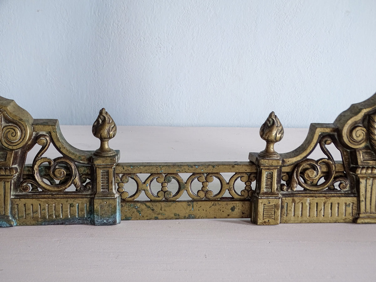 Pierced central brass fender section with repeating circular motifs and two small flame finials