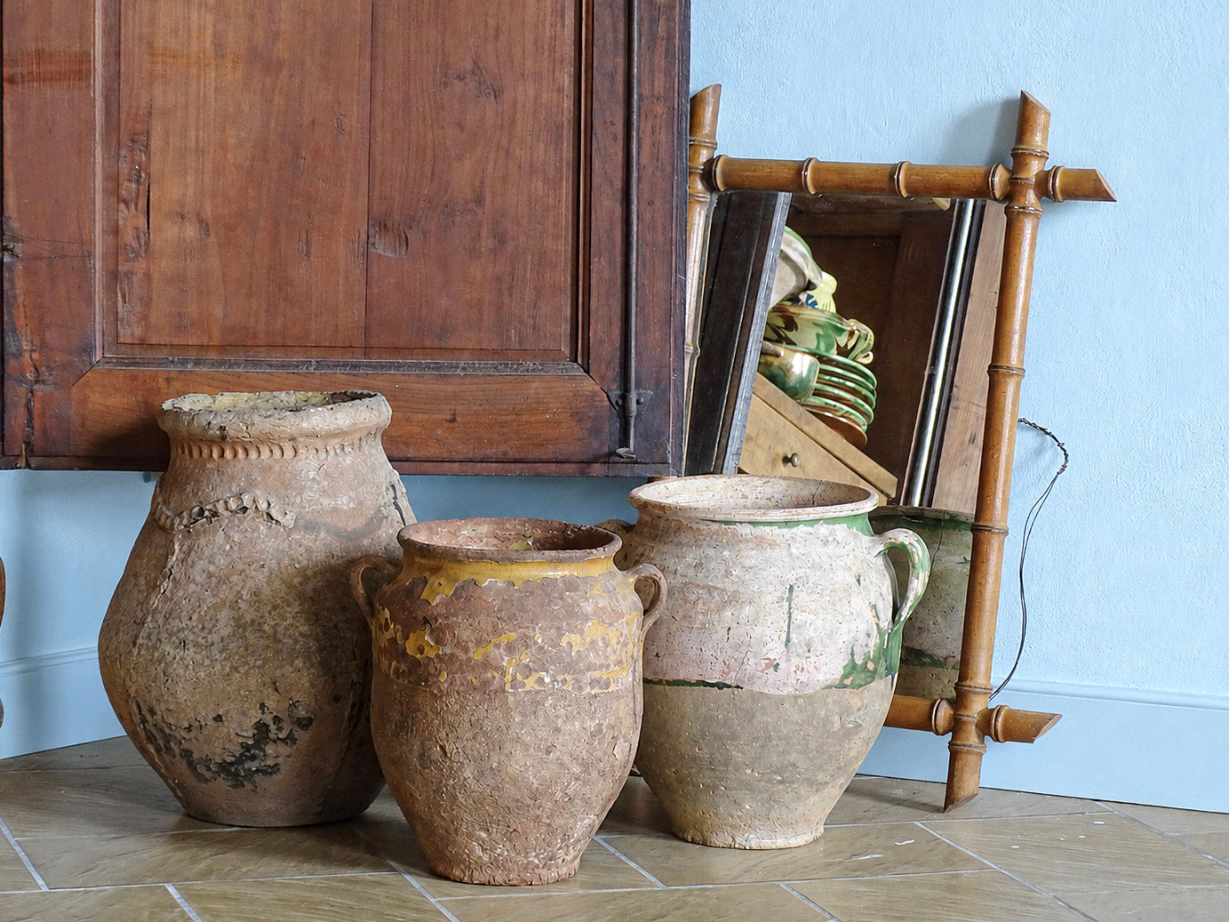 French antique earthenware pots including a ponne and confit pots in a blue painted room in a French country house. 