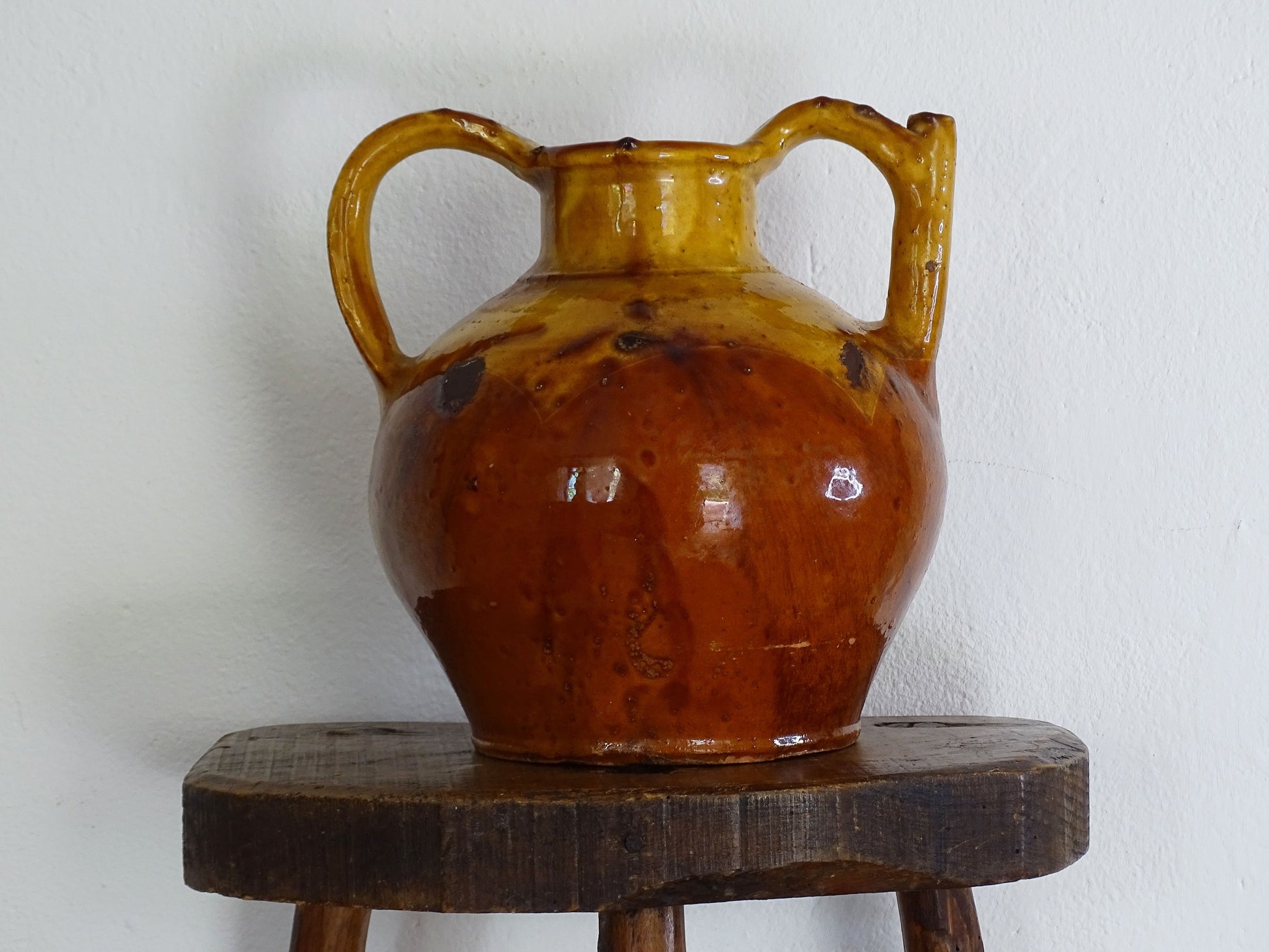 An antique French orjol or pitcher in golden caramel yellow glaze, pottery cruche or jug with two handles and spout from Languedoc in South of France.