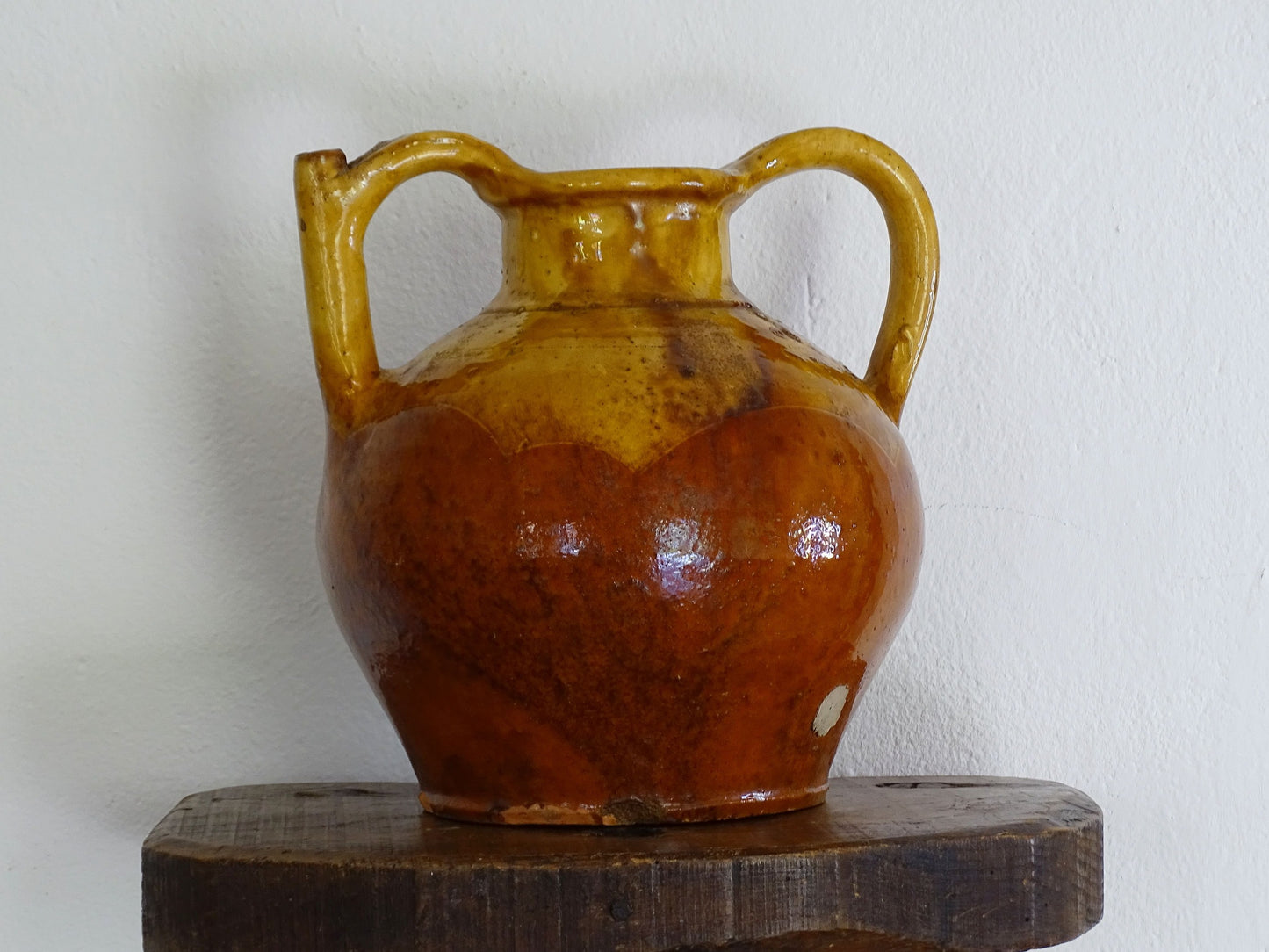 antique French orjol or pitcher in golden caramel yellow glaze, pottery cruche or jug with two handles and spout from Languedoc in South of France.