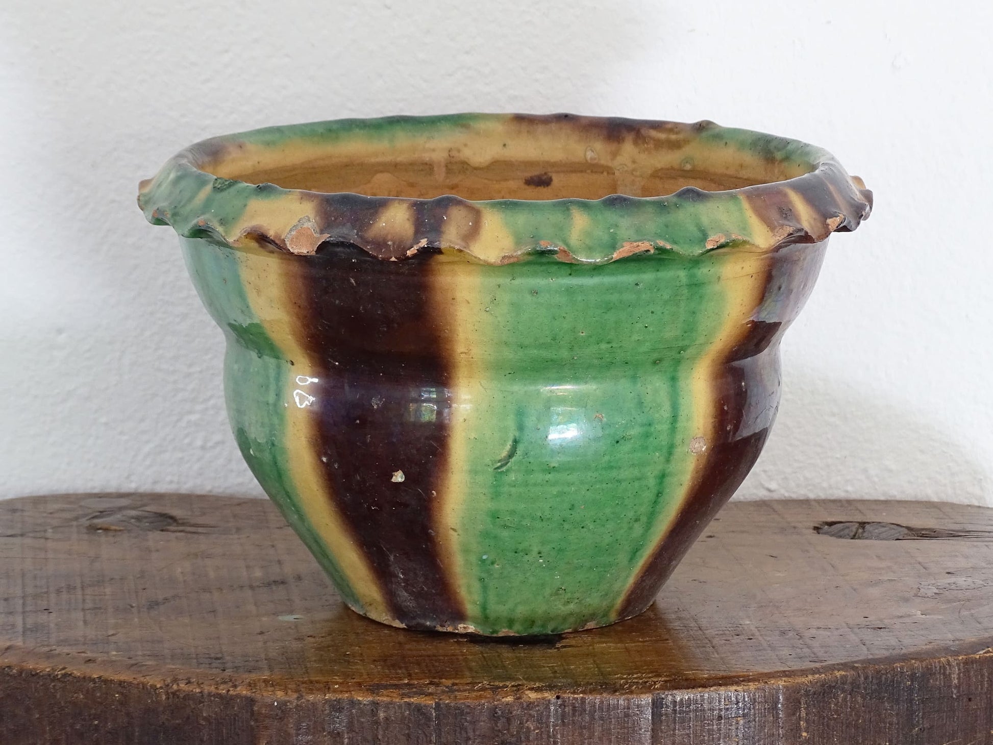 Antique French terracotta planter with drip glaze stripe in yellow, green and brown. The old earthenware cache pot has a crimped or pie crust edge.