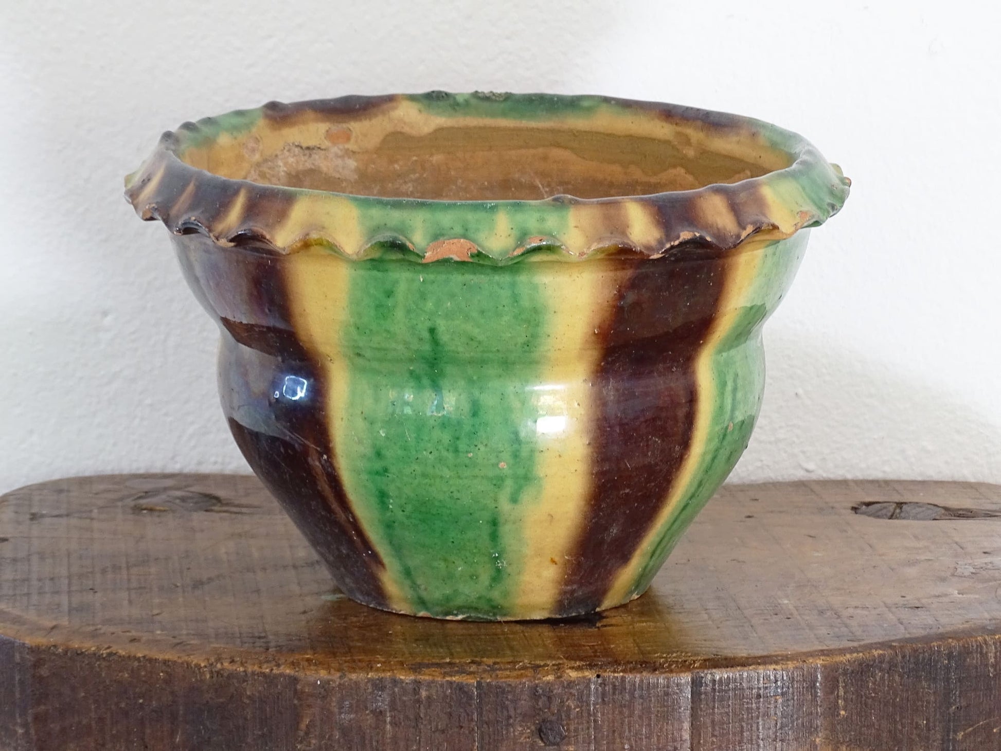 Antique French terracotta planter with drip glaze stripe in yellow, green and brown. The old earthenware cache pot has a crimped or pie crust edge.