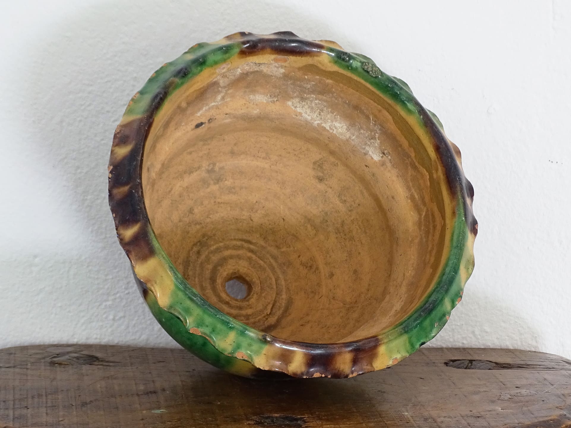 Antique French terracotta planter with drip glaze stripe in yellow, green and brown. The old earthenware cache pot has a crimped or pie crust edge.