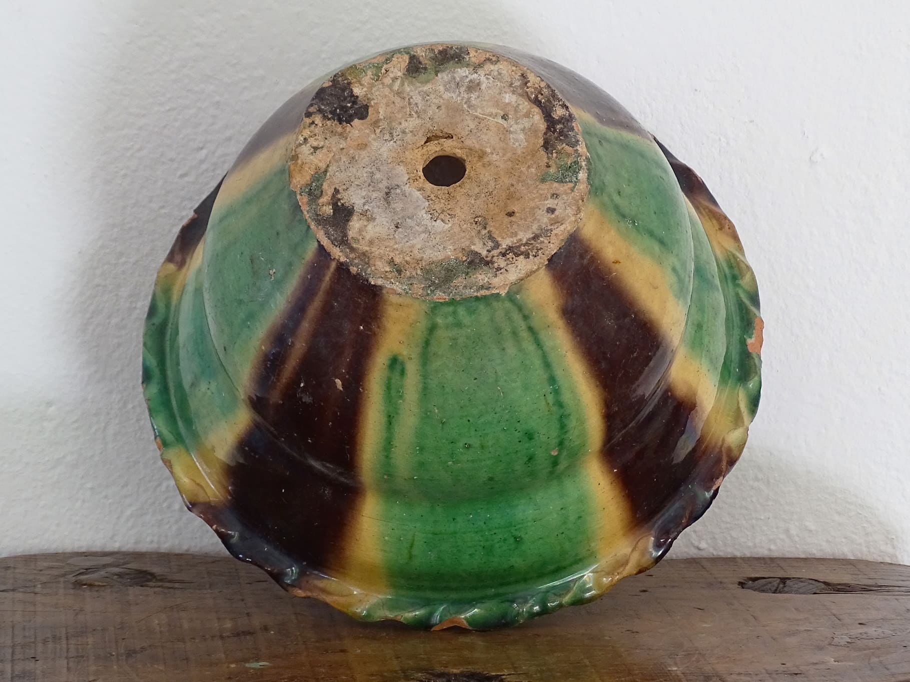 Antique French terracotta planter with drip glaze stripe in yellow, green and brown. The old earthenware cache pot has a crimped or pie crust edge.