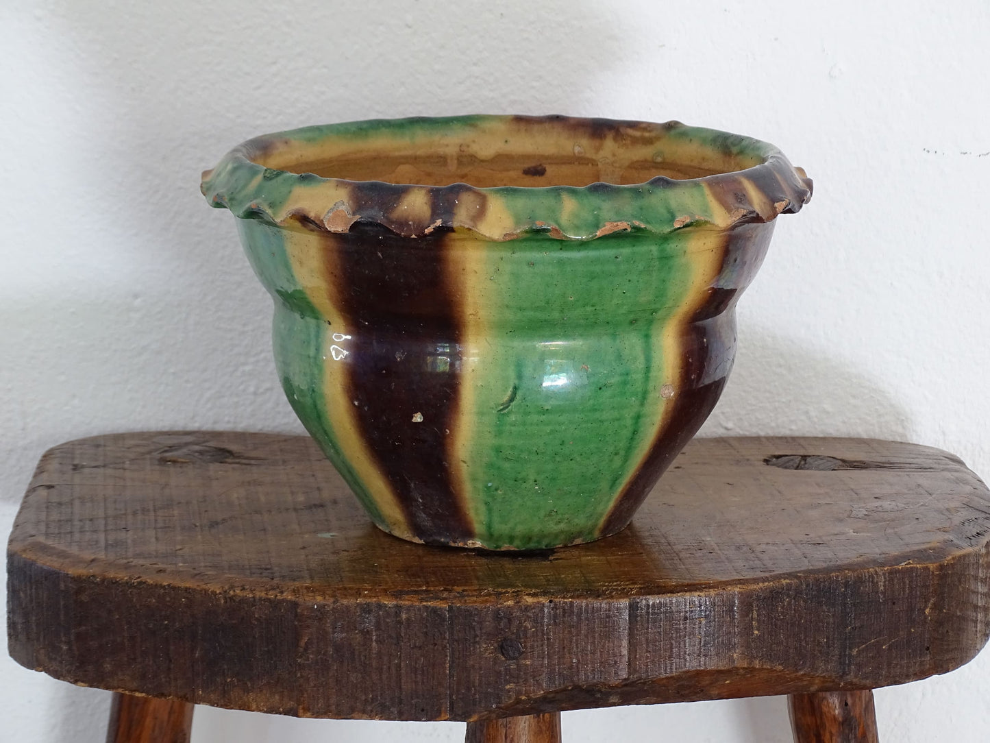 Antique French terracotta planter with drip glaze stripe in yellow, green and brown. The old earthenware cache pot has a crimped or pie crust edge.