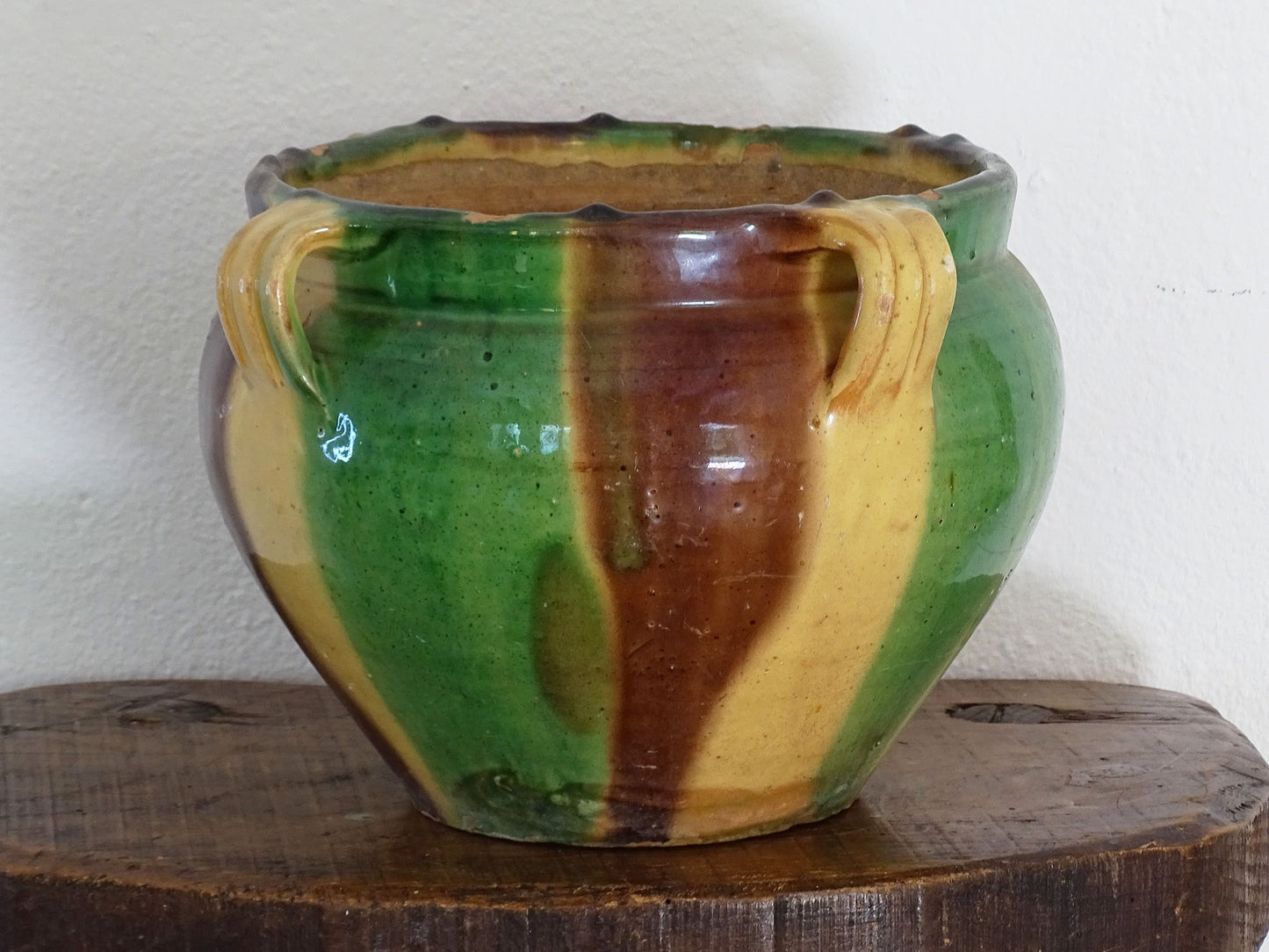 Antique French pottery planter or cache pot with a drip glaze stripe in yellow, green and brown. This earthenware terracotta pot has for handle and a timeworn appearance. 