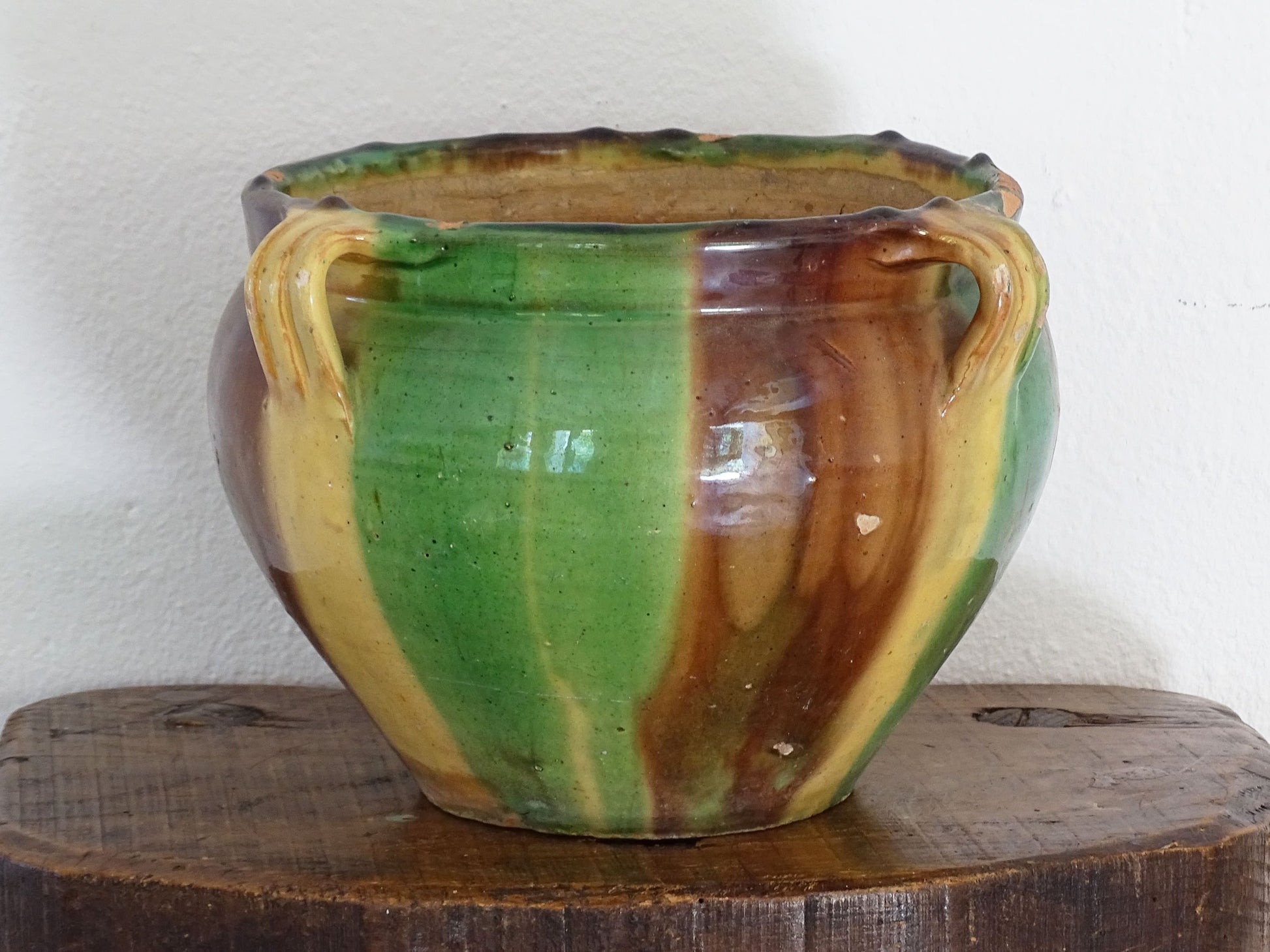 Antique French pottery planter or cache pot with a drip glaze stripe in yellow, green and brown. This earthenware terracotta pot has for handle and a timeworn appearance.