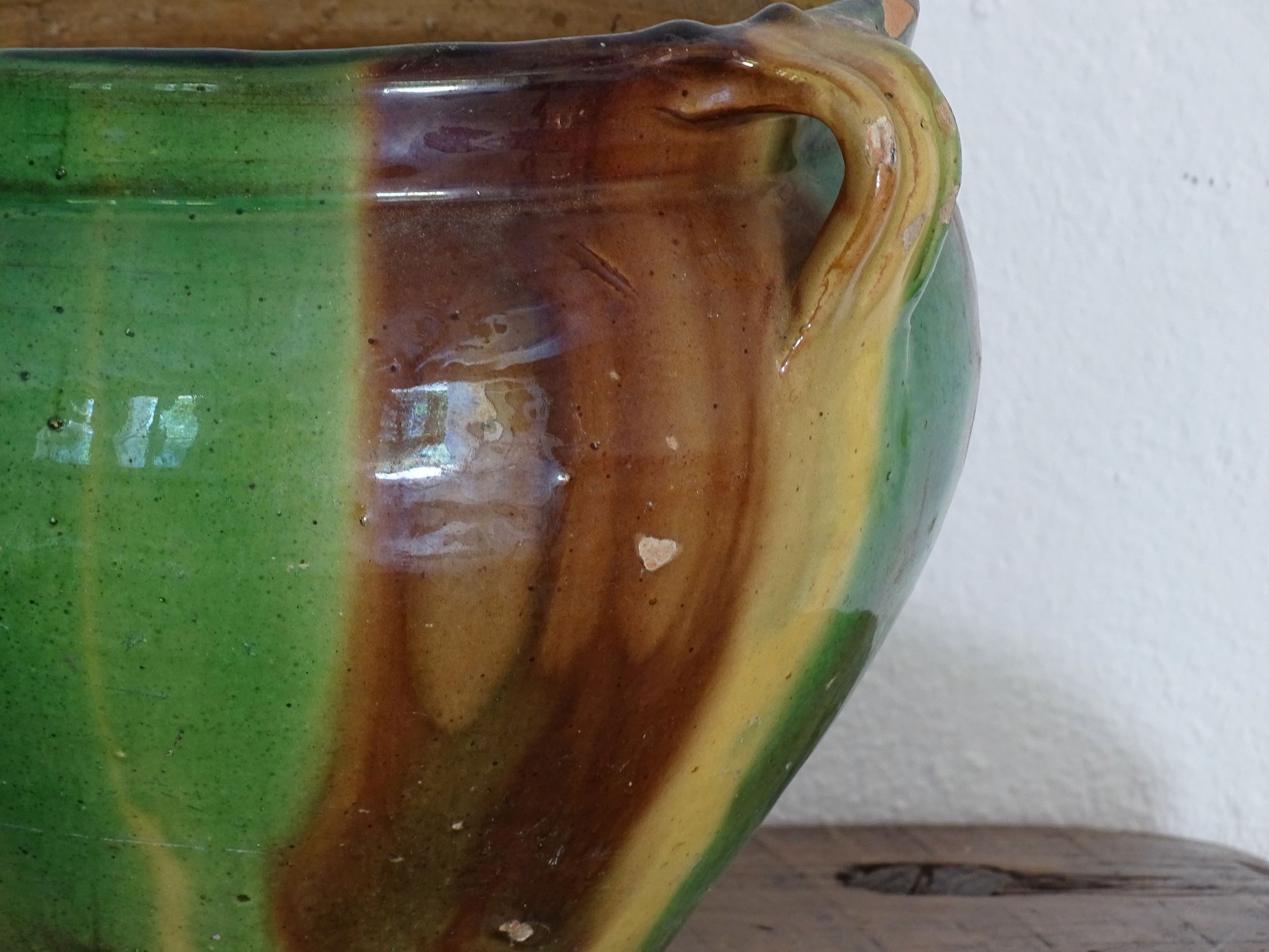 Antique French pottery planter or cache pot with a drip glaze stripe in yellow, green and brown. This earthenware terracotta pot has for handle and a timeworn appearance.