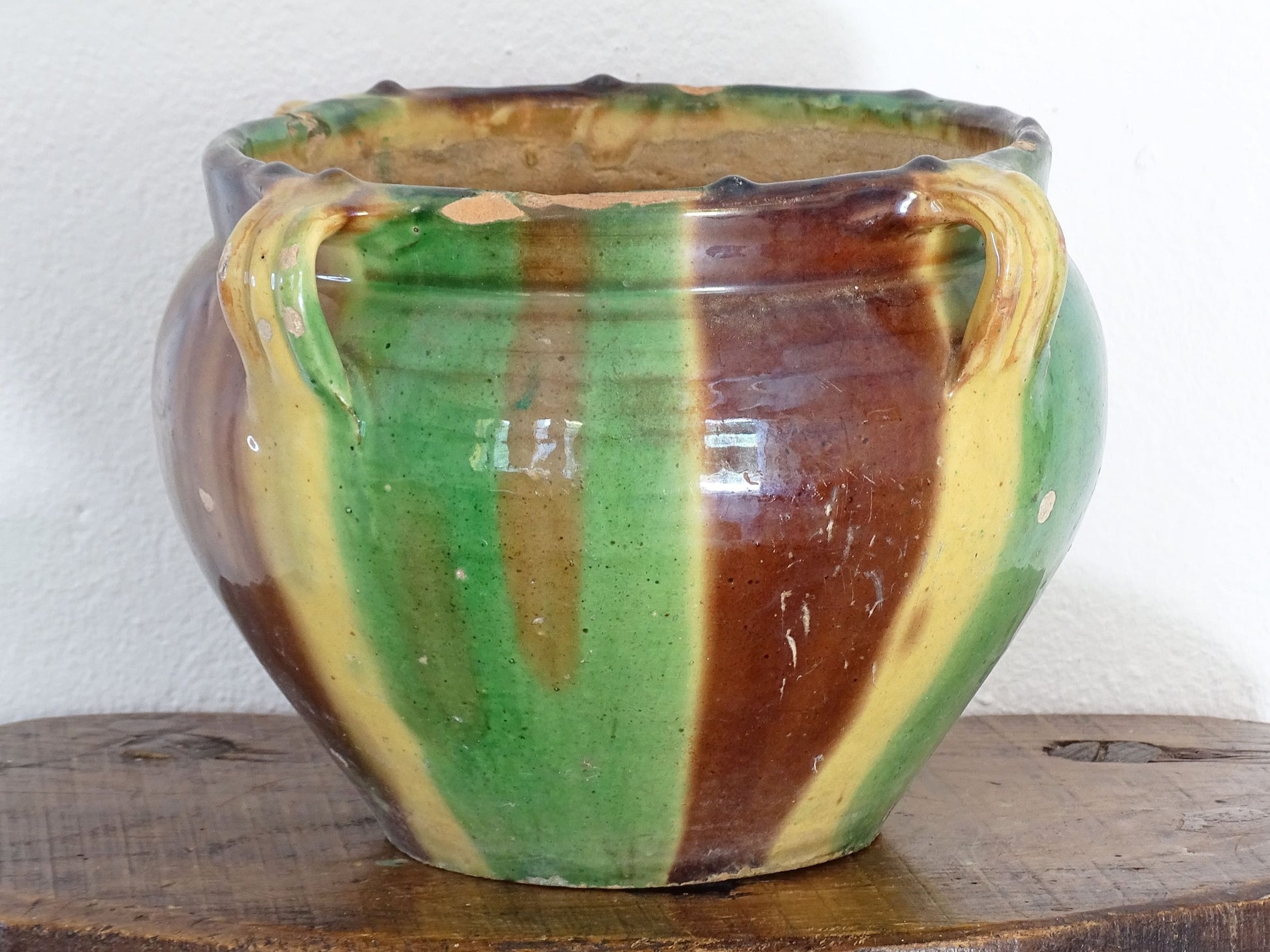 Antique French pottery planter or cache pot with a drip glaze stripe in yellow, green and brown. This earthenware terracotta pot has for handle and a timeworn appearance.