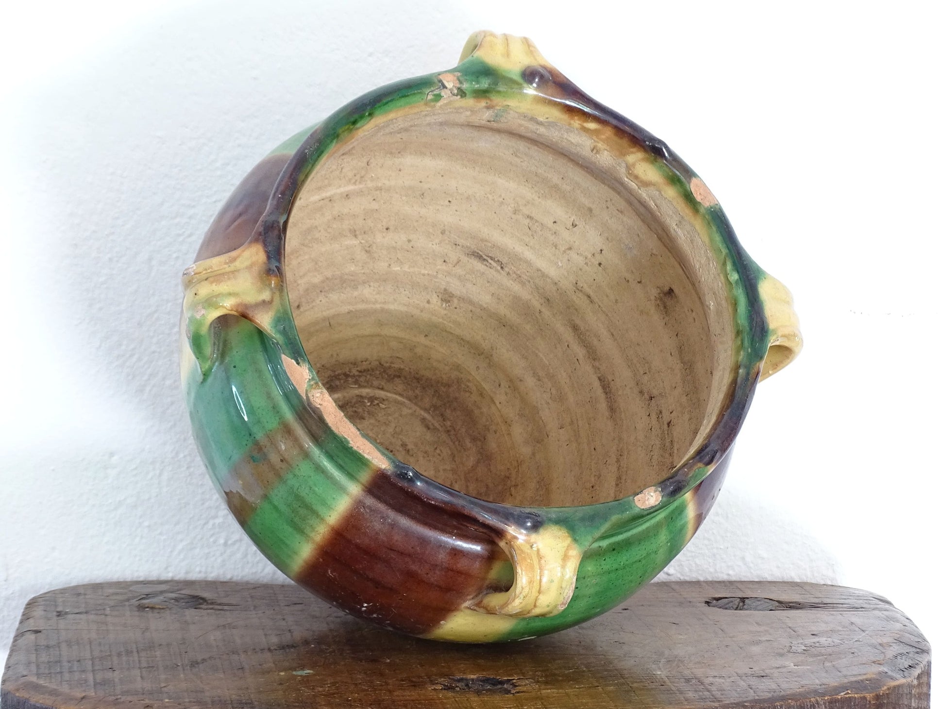 Antique French pottery planter or cache pot with a drip glaze stripe in yellow, green and brown. This earthenware terracotta pot has for handle and a timeworn appearance.