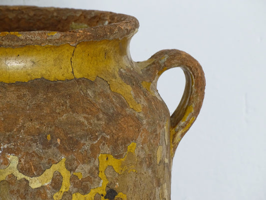 Antique French yellow confit pot, this 18th century terracotta confit pot with two handles is timeworn with patina. There is a yellow glaze to the top portion which is largely worn off.