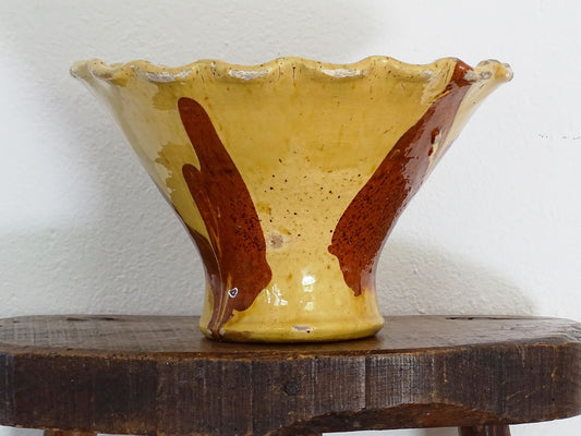 Antique French terracotta bowl with yellow glaze, this earthenware basin has sweeps of a red-brown tone to the body and a crimped, pie crust style edge.