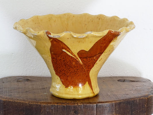 Antique French terracotta bowl with yellow glaze, this earthenware basin has sweeps of a red-brown tone to the body and a crimped, pie crust style edge.