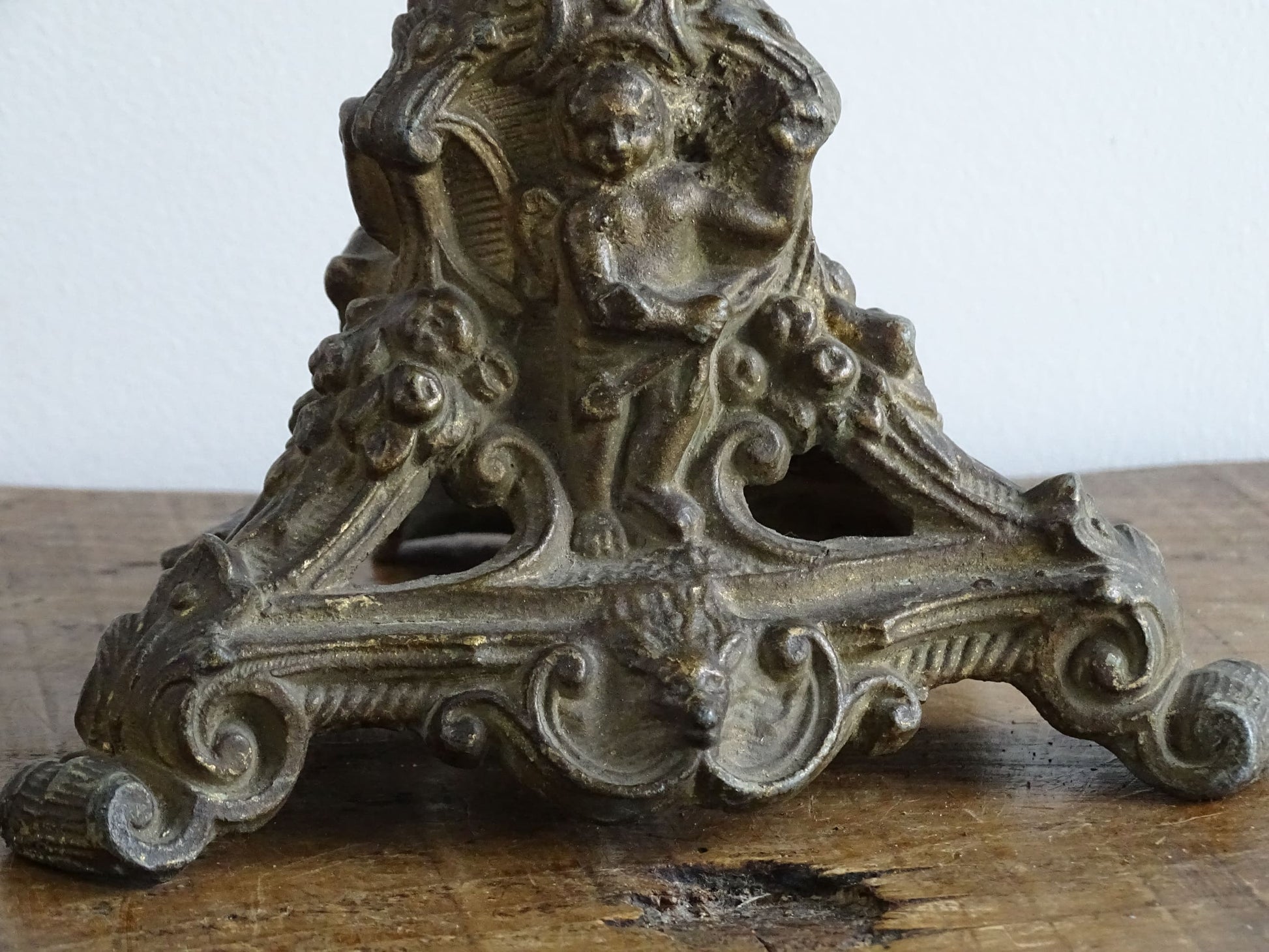 Ornate French antique cast iron candle holder with tripod base and decorated with cherubs. 