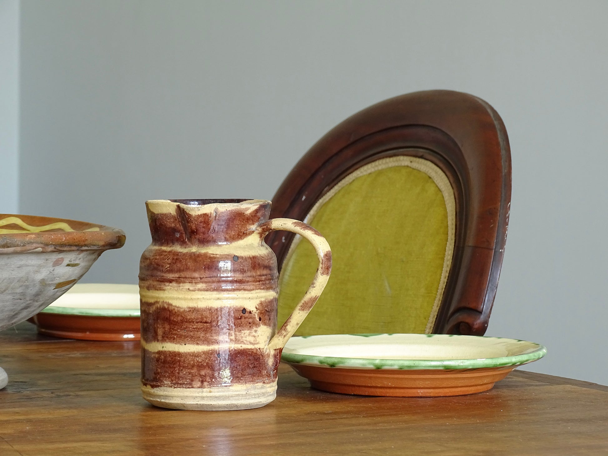 French antique ceramic pitcher with a yellow and brown glaze from Dieulefit  on a dining table in a French country home. 