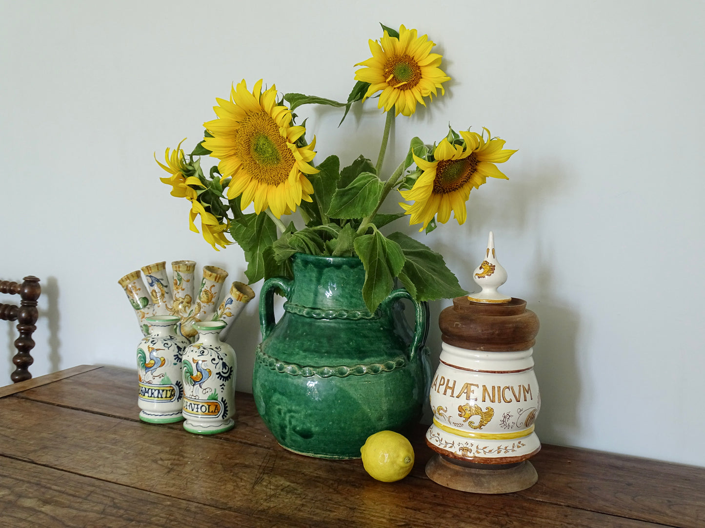 French vintage ceramic pharmacy jar with wooden lid and base on a sideboard with ceramic vases in a French country home. 